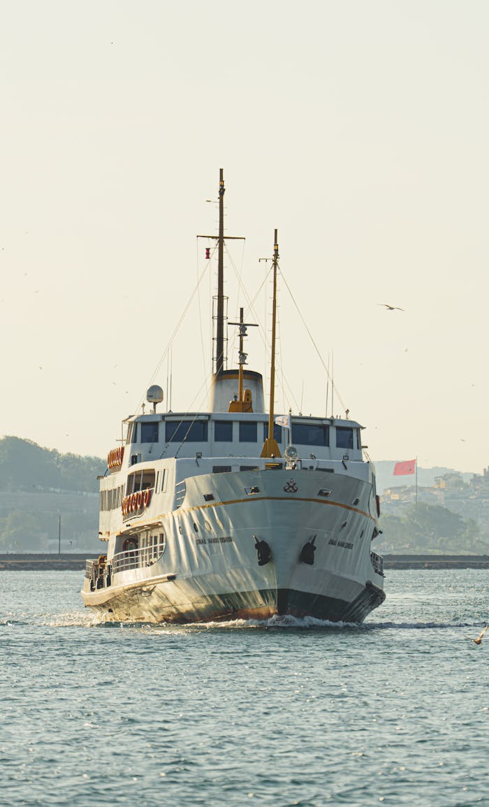 services-01 A classic ferry sails gracefully through a calm sea under a bright sky, creating a serene travel scene.