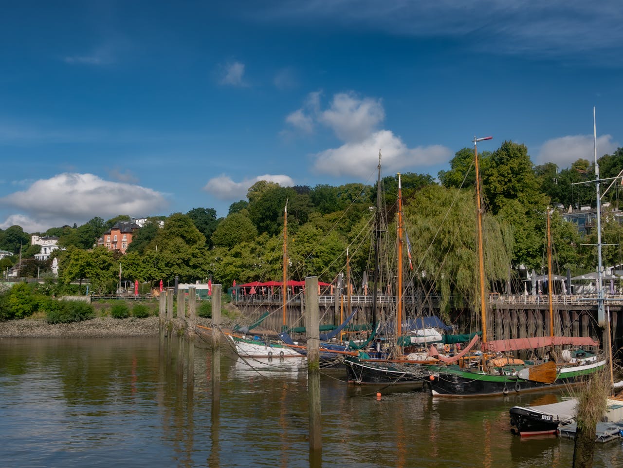 services-03 A picturesque view of Hamburg's old port featuring traditional sailing ships docked under a clear blue sky.